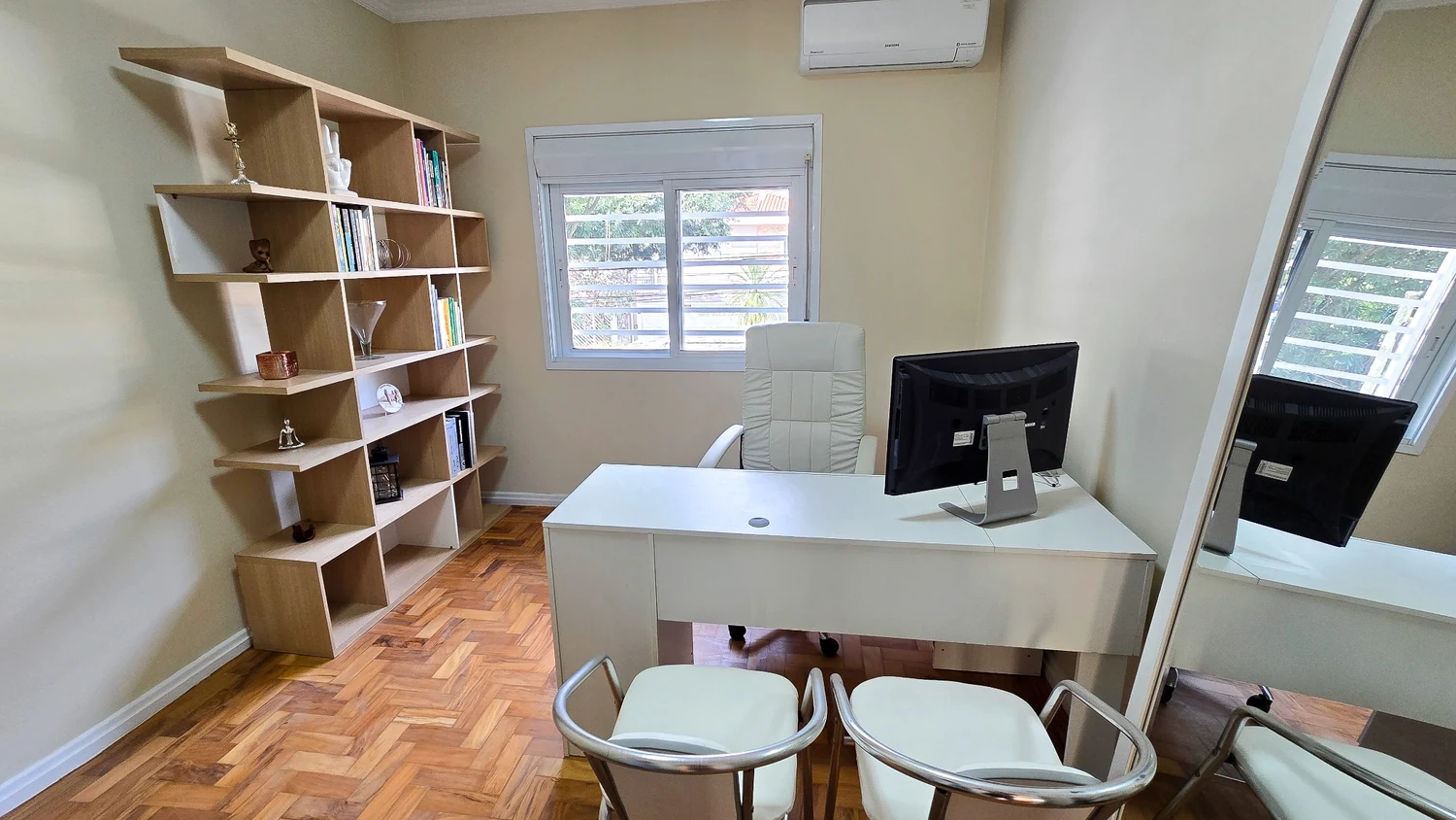Sala do Instituto Turano, com mesa branca, cadeiras e estante